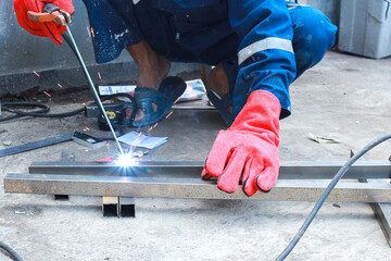 Welder's hand with gloves welding the steelwork of iron bar with sparking light and smoke