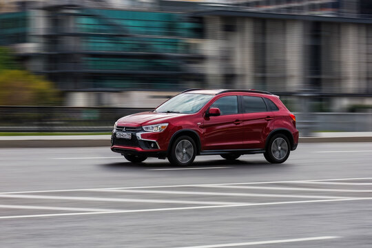 Mitsubishi asx SUV vehicle on the city road. Fast moving red car on Moscow streets. Accelerating with low-emission. Compliance with speed limits on the road