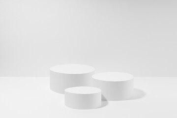 Abstract set of three white round podiums for cosmetic products, mockup on white background. White stage template in elegant simplicity style for showing products, advertising, design, poster, text.