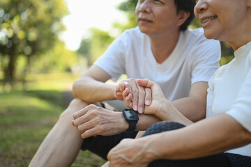 Shot of a happy senior couple dressed in sportswear holding hands and relaxing in the park.