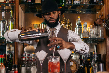 Black bartender preparing a cocktail in a traditional cocktail bar