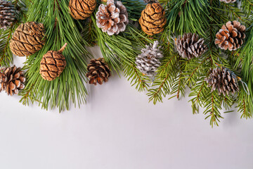 A Christmas composition. A frame of pine and fir branches and fir cones and Christmas balls and decorations on a white background. Flat layout, top view, copy space