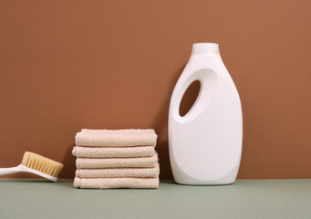 Laundry day. A stack of clean towels, laundry detergent and a brush.