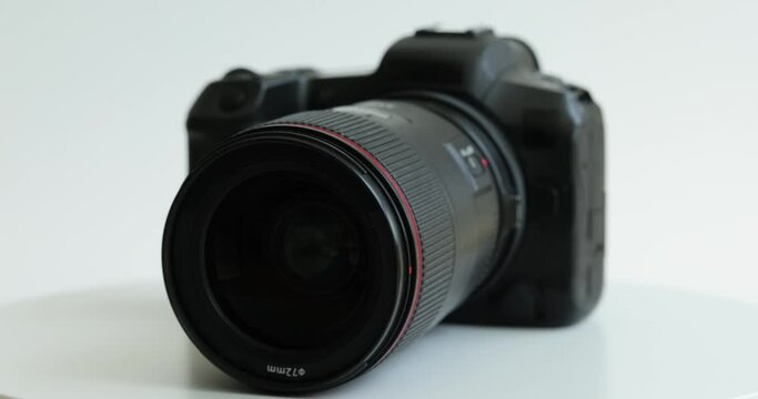 Black photo camera with lens rotating on white background closeup. Choosing professional camera