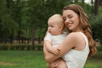 Mother with her cute baby spending time together outdoors. Space for text