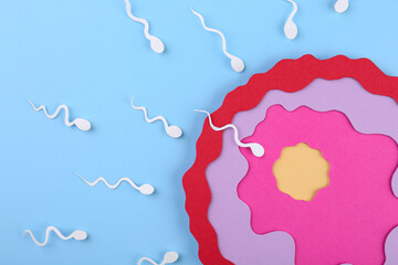 Fertilization concept. Sperm cells swimming towards egg cell on light blue background, top view