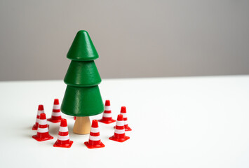 A pine tree is surrounded by traffic cones. Preserve forests from deforestation during Christmas...