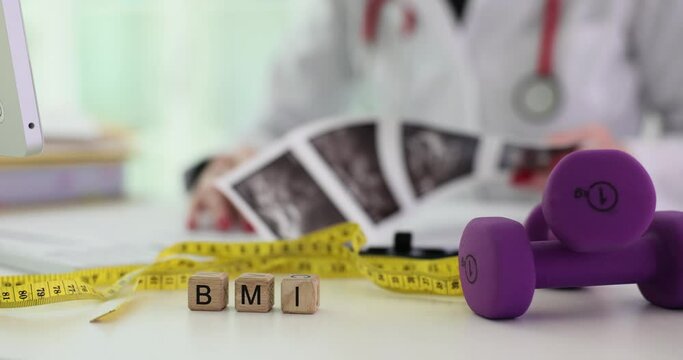 Dumbbell measuring tape and word BMI in wooden block and doctor. Healthy nutrition sport and human health