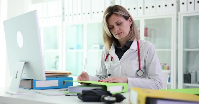 Doctor puts documents in folder in clinic. Therapist or nurse working with medical records