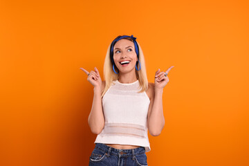 Smiling hippie woman pointing at something on orange background