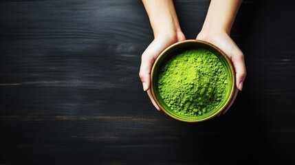 Matcha tea powder in a wooden plate on dark background with whisk, top view, copy space. Generative AI