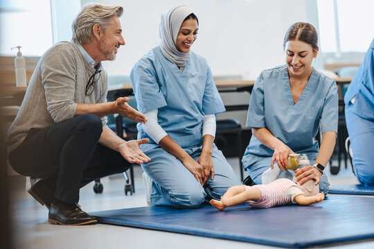 Female nursing students using infant CPR simulator in medical paediatric training