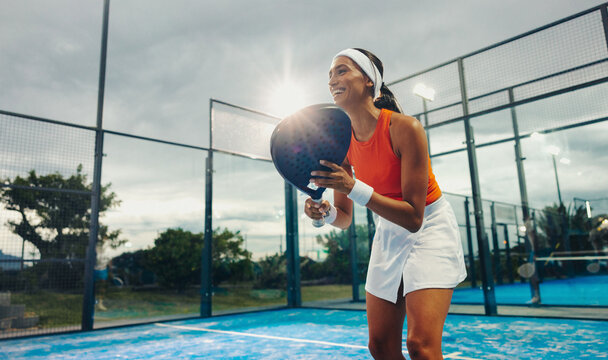 Ready and smiling: Young female athlete training on padel court