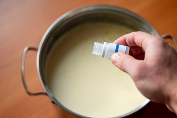 Putting ferment into milk in order to make yogurt, close up. Home cooking, diary product, good for health concepts