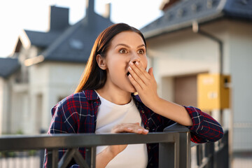 Concept of private life. Curious young woman spying on neighbours over fence outdoors
