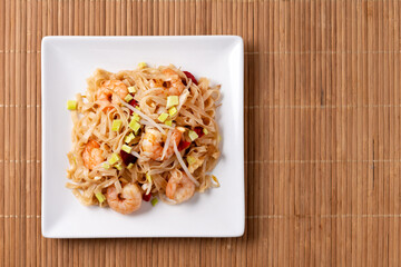 Pad Thai with shrimp and vegetables on wooden table. Top view. Copy space
