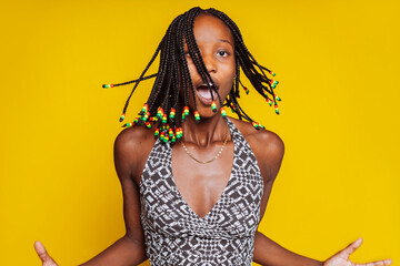 Fashion young african woman in black and white top dancing over yellow background. Pretty girl with...