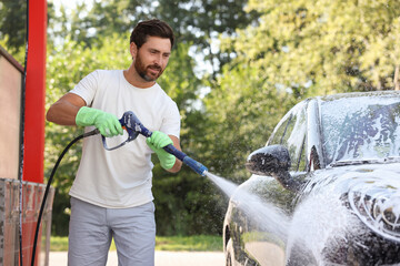 Man covering automobile with foam at outdoor car wash