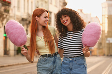 Happy friends with cotton candy on city street