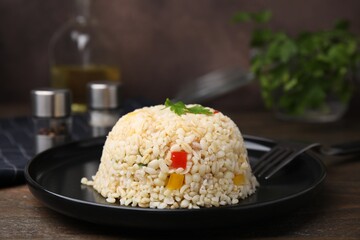 Delicious bulgur with vegetables and parsley served on wooden table, closeup
