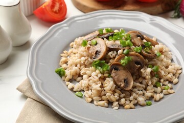Delicious pearl barley with onion and mushrooms on white table, closeup