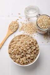 Delicious pearl barley served on white tiled table, flat lay