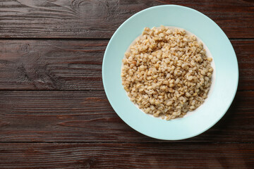 Delicious pearl barley on wooden table, top view. Space for text