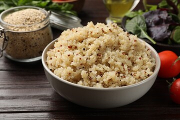 Tasty quinoa porridge in bowl on wooden table, closeup