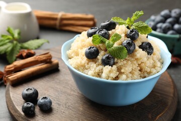 Tasty quinoa porridge with blueberries and mint in bowl on table, closeup