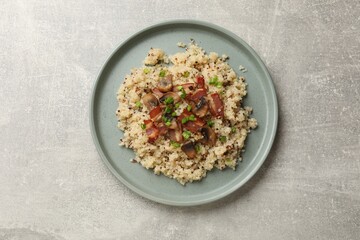 Plate of tasty quinoa porridge with fried bacon, mushrooms and green onion on light grey table, top view