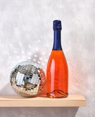 A bright bottle of champagne and a glittering disco ball. Concept of party and celebration.
