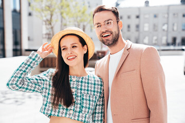 Naklejka premium Beautiful fashion woman and her handsome elegant boyfriend in beige suit. Sexy brunette model in summer clothes. Fashionable smiling couple posing in street Europe. Brutal man and female outdoors