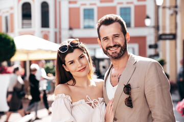 Beautiful fashion woman and her handsome elegant boyfriend in jacket. Sexy brunette model in summer clothes. Fashionable smiling couple posing in street Europe. Brutal man and female outdoors
