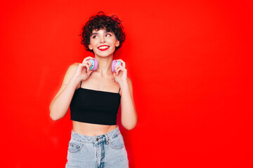 Young beautiful smiling female in trendy summer tank top. Carefree woman posing near red wall in...