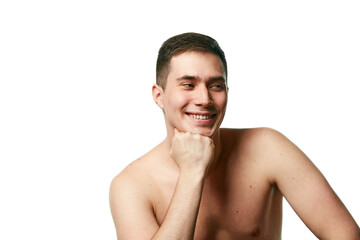 Attractive man, well-groomed guy with bare shoulders smiling and touching chin looking away against white background. Concept of beauty treatment and hygiene, body care, anti-aging procedures.