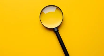Fotobehang close up of a magnifying glass on a yellow background searching for job with copyspace of white paper to write  © K