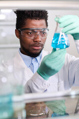 Vertical close up portrait of African American male medical laboratory technician wearing safety...