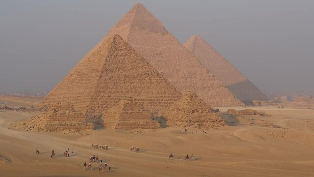 Cairo, Egypt: Tourists enjoy a ride in a horse cart by the famous Great Pyramid of Egypt in Giza in the desert at the limit of Cairo city. 