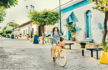 Beautiful and happy girl riding a bicycle on the street of La Calzada, Granada, Nicaragua. Tourist...