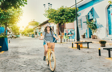 Smiling tourist woman riding a bicycle on the streets of Granada. Beautiful girl riding a bicycle...