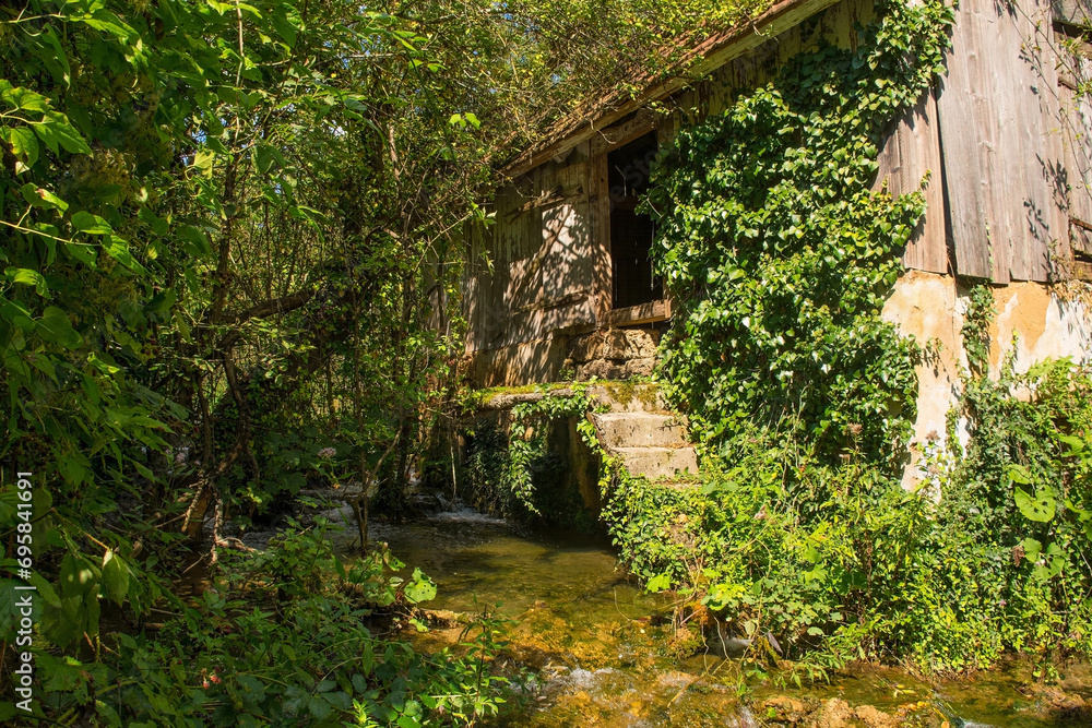 Wall mural An abandoned derelict building next to a stream in Martin Brod in the Una National Park. Una-Sana Canton, Federation of Bosnia and Herzegovina. Early September