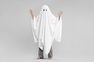 Woman in white ghost costume on light grey background. Halloween celebration