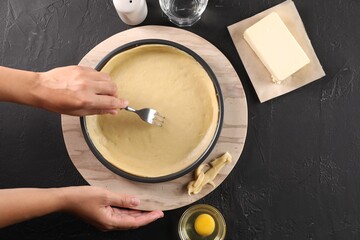 Woman making quiche at black table, top view
