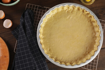 Pie tin with fresh dough and ingredients on wooden table, flat lay. Making quiche