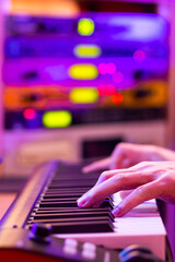 male musician hands playing midi piano on blurred sound module, audio interface background for recording in studio
