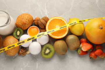 Allergenic food. Different fresh products with tape on gray marble table, top view