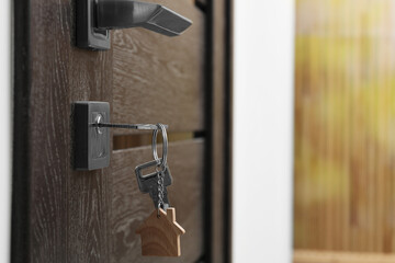 Door with key and keychain in shape of house. Space for text