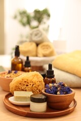 Dry flowers, loofah, soap bar, bottle of essential oil and jar with cream on wooden table indoors. Spa time