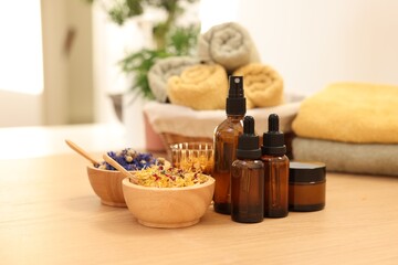 Dry flowers, bottles of essential oils and jar with cream on wooden table indoors. Spa time