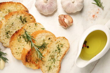 Tasty baguette with garlic, dill, rosemary and oil on table, flat lay